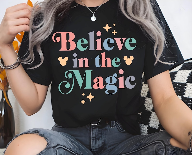 a woman with grey hair wearing a black t - shirt that says believe in the