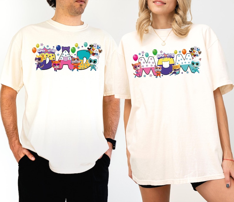 A man and a woman wearing matching white t-shirts with colorful cartoon characters and text.
