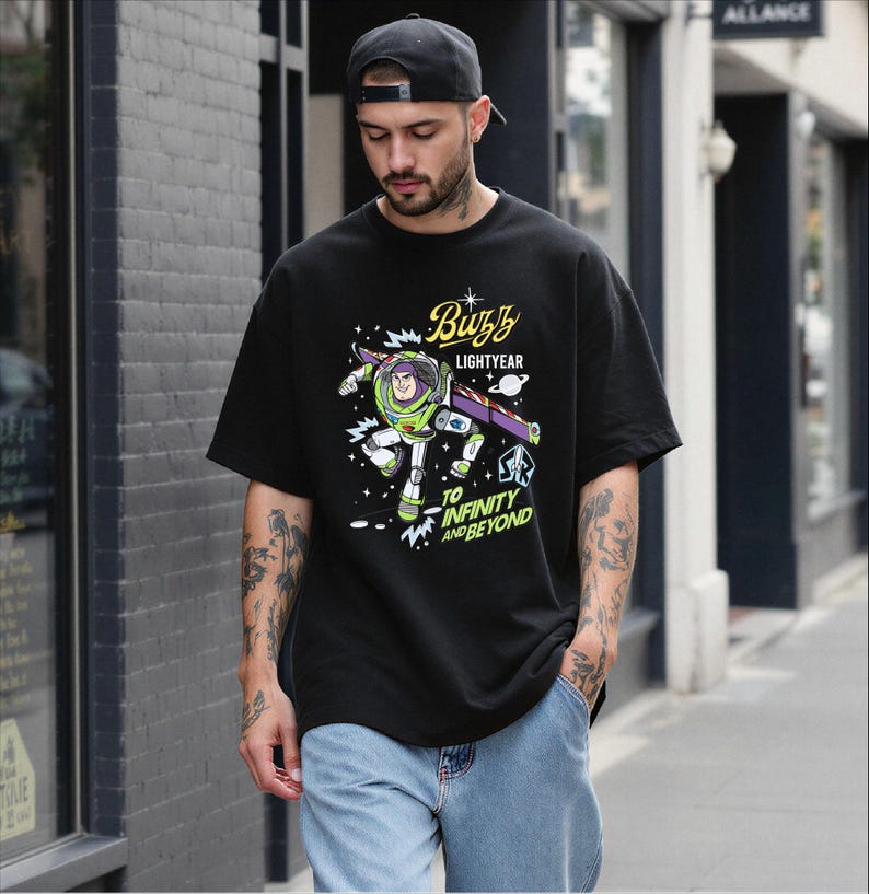 A man wearing a black t-shirt with a graphic of Buzz Lightyear from the Toy Story franchise, standing on a city street.