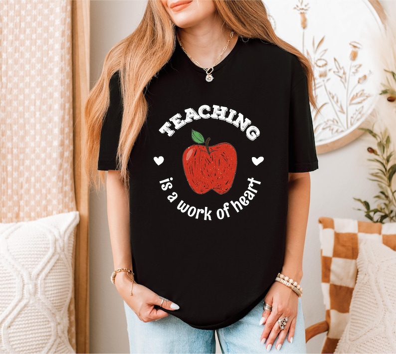 a woman wearing a teaching is a work of heart t - shirt