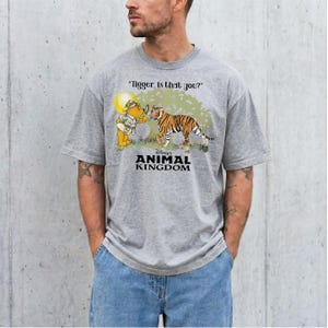 A man wearing a grey t-shirt with a graphic design depicting a tiger and a character from Winnie the Pooh.