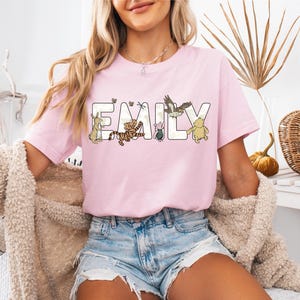 a woman sitting on a bench wearing a pink t - shirt