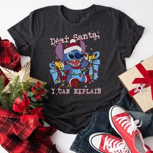 a black t-shirt with a cartoon character and text, along with Christmas-themed items such as a gift box, a red bow, and a pair of red sneakers.