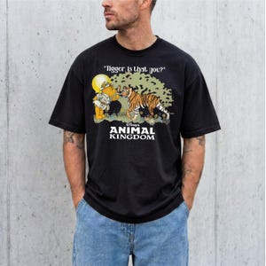 A man wearing a black t-shirt with a graphic design featuring a tiger and Winnie the Pooh characters from the Disney animated film "Animal Kingdom".