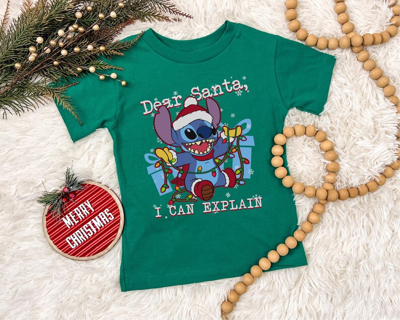 a green t-shirt with a cartoon character and text, along with Christmas decorations such as a Christmas tree, ornaments, and beads.