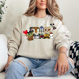 a woman sitting on a couch wearing a mickey mouse sweatshirt