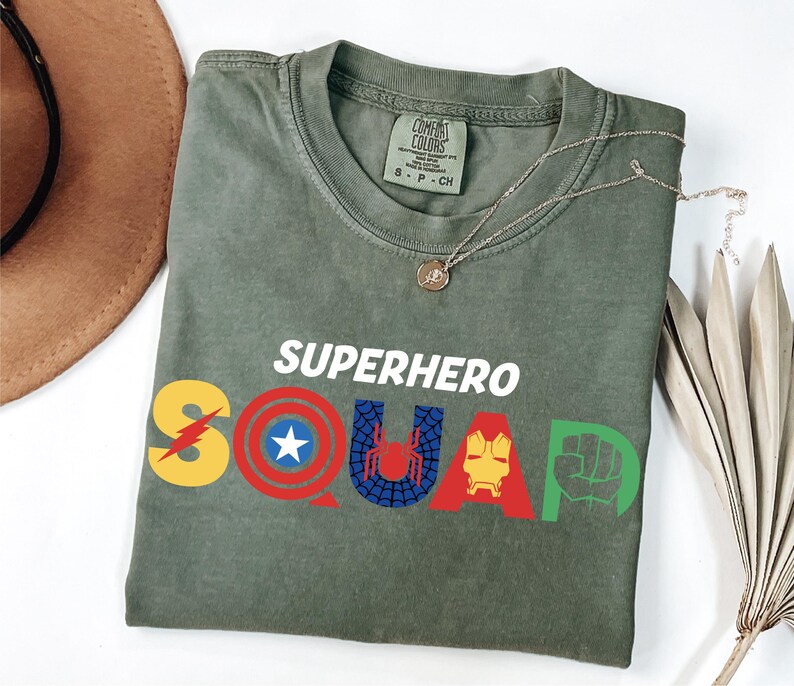 a t - shirt that says superhero squad next to a hat