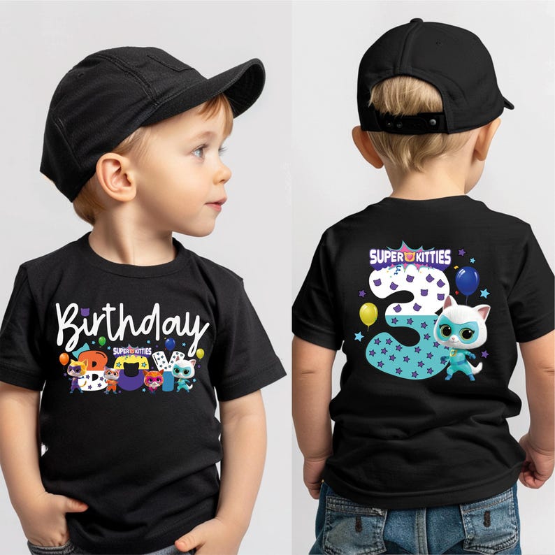 A young boy wearing a black t-shirt with a birthday theme and a cap, standing against a white background.
