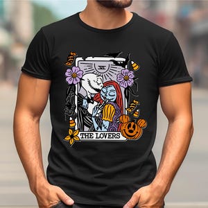A black t-shirt with a graphic design featuring a couple embracing, surrounded by various Halloween-themed elements such as pumpkins, bats, and flowers.