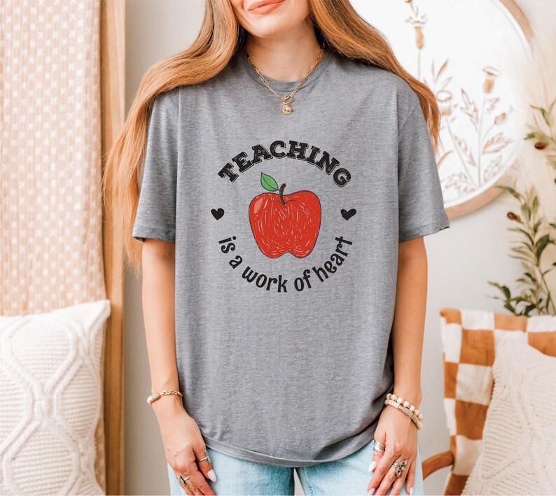 a woman wearing a teaching is a work of heart t - shirt