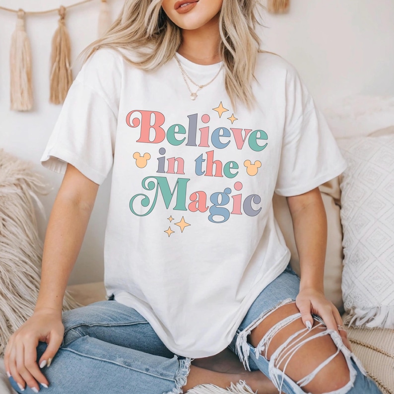 a woman sitting on a bed wearing a t - shirt that says believe in the
