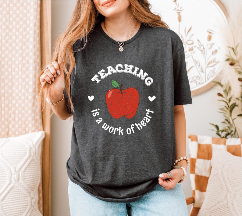 a woman wearing a teaching is a work of heart t - shirt