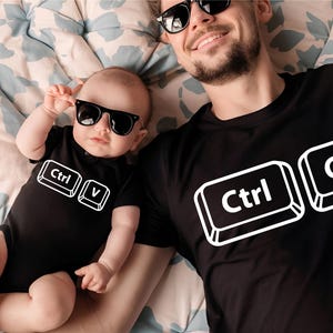 May include: Black t-shirt and baby onesie set with matching "Ctrl C" and "Ctrl V" keyboard key graphics. Both are wearing black sunglasses. The baby is wearing a black onesie with the "Ctrl V" graphic.