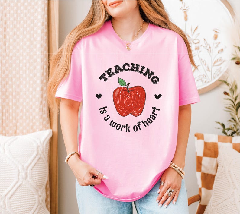a woman wearing a pink teaching is a work of heart t - shirt