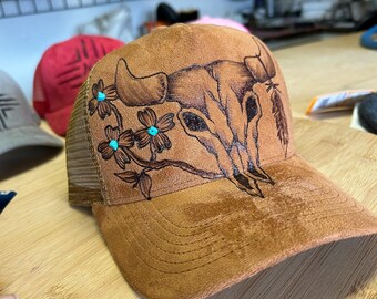 手焼きの牛の頭蓋骨トラッカーハット – 花柄とターコイズブルーのアクセントが付いたウエスタン風のダメージ加工メッシュキャップ