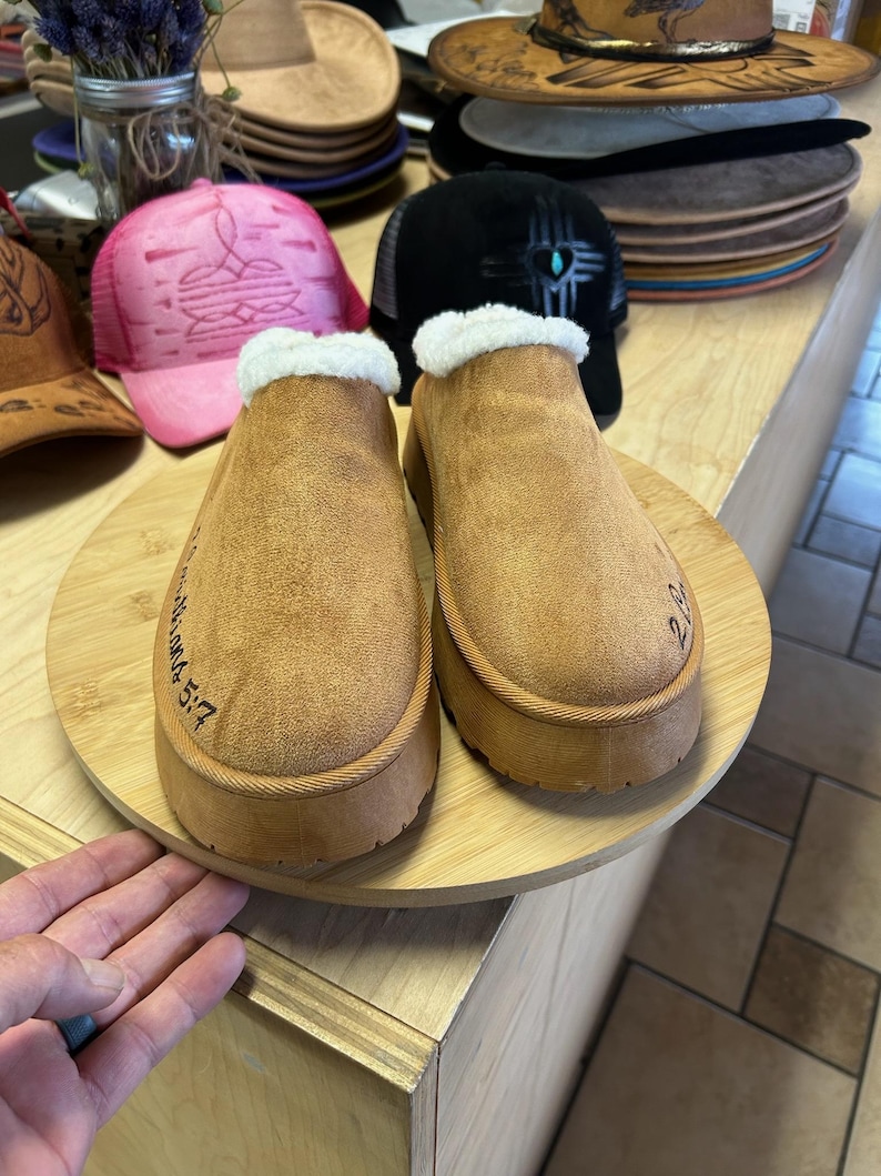 Faith-based engraved slippers with 2 Corinthians 5:7 surrounded by artisan hats and handmade accessories.