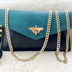 Clutch tipo sobre de piel Pueblo italiana con correa de muñeca y cadena dorada para el hombro.