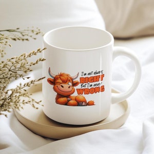 Peut inclure: Une tasse en céramique blanche avec une illustration de vache Highland brune et blanche. La tasse porte l'inscription "I'm not always RIGHT But I'm never WRONG".