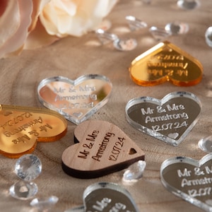 Peut inclure: Assortiment de faveurs de mariage en forme de cœur en or, argent et bois. Les faveurs sont gravées avec le texte "Mr & Mrs Armstrong" et la date "12.07.24".