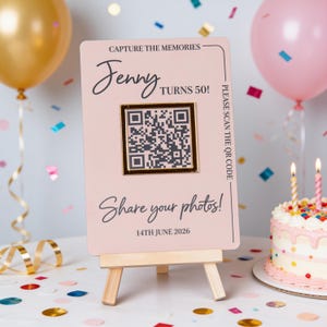 May include: A rectangular light pink sign on a small wooden easel featuring the text "CAPTURE THE MEMORIES", "Jenny TURNS 50!", "PLEASE SCAN THE QR CODE", "Share your photos!", and "14TH JUNE 2026" with a central square QR code in a gold frame.