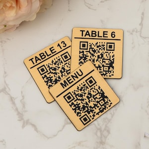 May include: Three wooden table number signs with black text and QR codes. The signs read "TABLE 6", "TABLE 13", and "MENU".