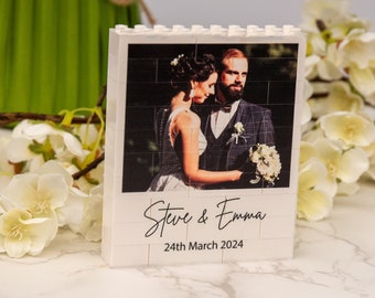 May include: White Lego brick photo frame with a picture of a bride and groom. The frame has the text "Steve & Emma" and "24th March 2024" printed on it.
