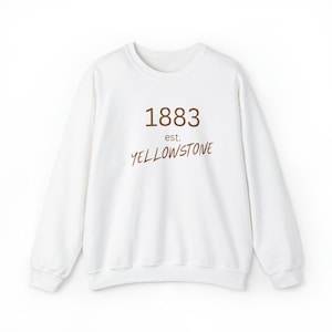 Könnte beinhalten: Weißer Langarm-Pullover mit braunem Text, der "1883 est. YELLOWSTONE" lautet.