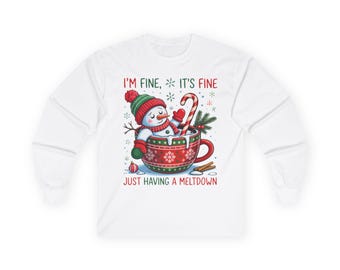 May include: White long-sleeve shirt with a graphic of a snowman in a red and green hat and mittens, inside a red and green mug with a candy cane. The text reads "I'M FINE, IT'S FINE JUST HAVING A MELTDOWN."