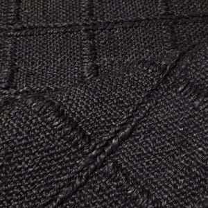 May include: A dark charcoal gray rug featuring a prominent grid pattern created by raised, thick woven lines. The surface has a dense, textured appearance with a consistent weave throughout, showcasing a repeating square design across the fabric.