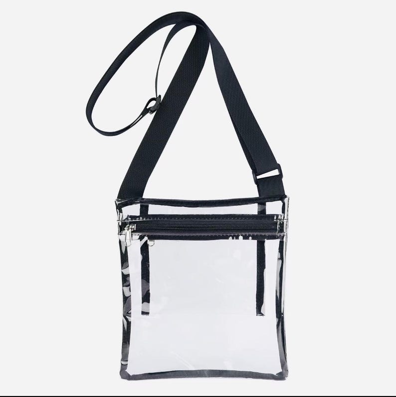 Peut inclure: Sac bandouli&egrave;re transparent avec une bandouli&egrave;re noire r&eacute;glable et une fermeture &eacute;clair noire. Le sac est rectangulaire et transparent, permettant de voir le contenu. La bandouli&egrave;re mesure environ 122 cm.