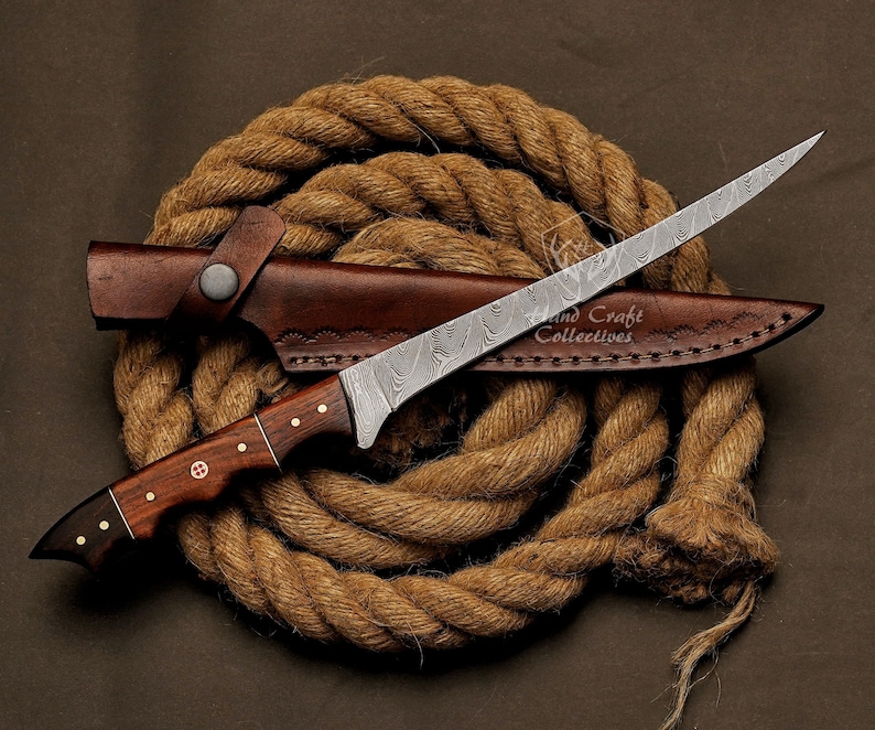 May include: A brown leather sheath with a Damascus steel blade knife with a wooden handle. The knife is wrapped in a brown rope.