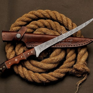 May include: A brown leather sheath with a Damascus steel blade knife with a wooden handle. The knife is wrapped in a brown rope.