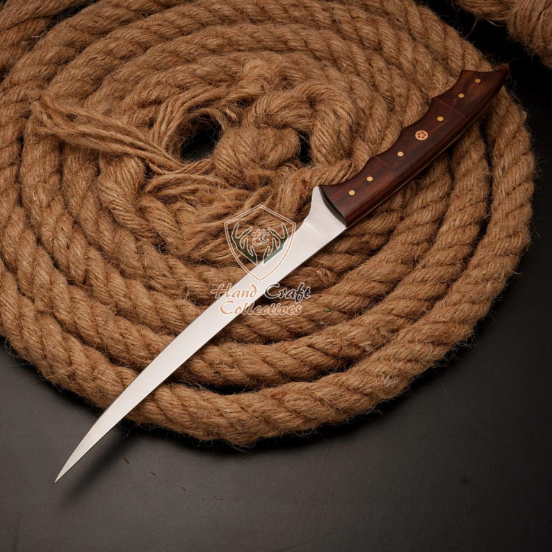 May include: A long, thin, silver knife with a wooden handle. The handle is dark brown with brass accents. The knife is lying on a coil of brown rope.