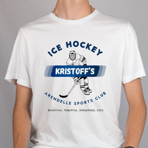 May include: White t-shirt with a blue and white graphic of an ice hockey player. The graphic says "Ice Hockey Kristoff's Arendelle Sports Club" and "Beautiful. Powerful. Dangerous. Cold."