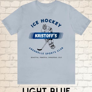 May include: Light blue t-shirt with a graphic of an ice hockey player and the text "ICE HOCKEY KRISTOFF'S ARENDELLE SPORTS CLUB BEAUTIFUL, POWERFUL, DANGEROUS, COLD"