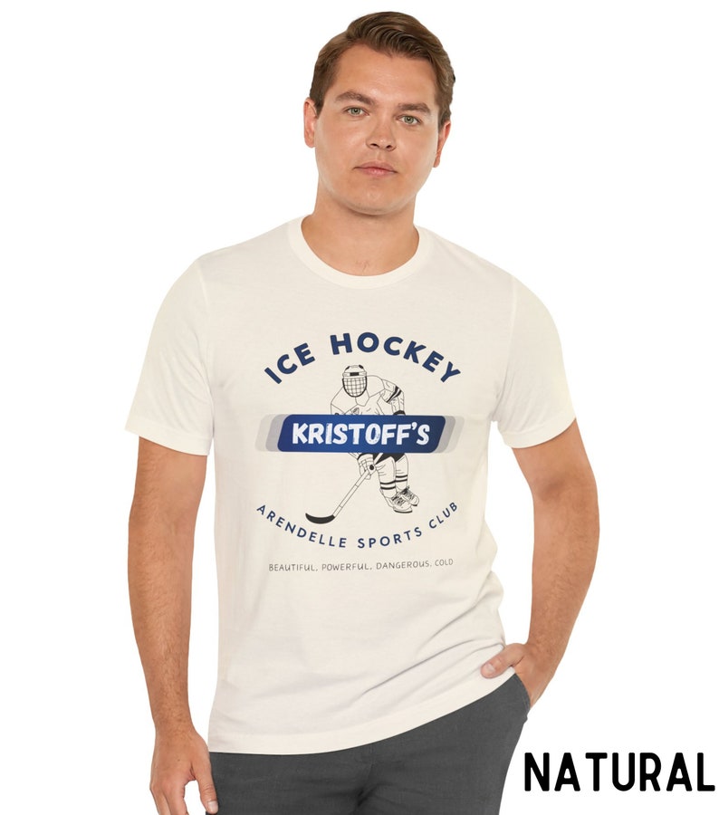 May include: White t-shirt with a blue graphic of an ice hockey player. The graphic says "ICE HOCKEY KRISTOFF'S ARENDELLE SPORTS CLUB BEAUTIFUL. POWERFUL. DANGEROUS. COLD."
