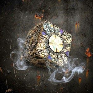 May include: A decorative puzzle box featuring a complex gold and black geometric pattern with intricate engravings and a central circular gold disc on each face, surrounded by wisps of white smoke against a dark, weathered, rusted metal background.