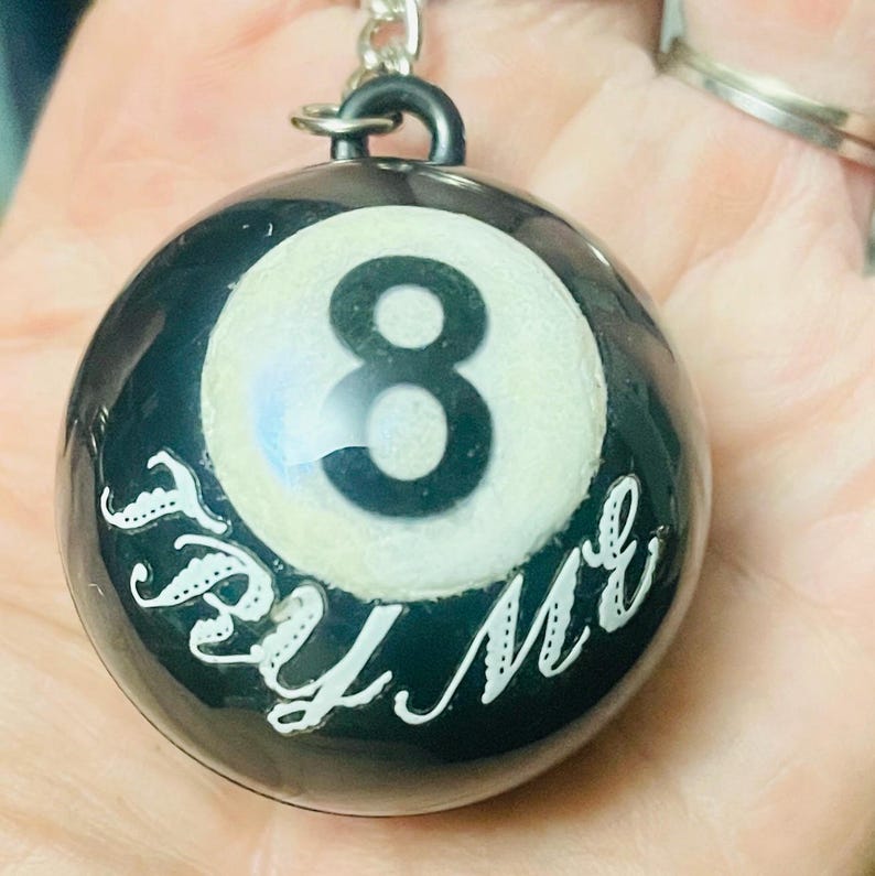 May include: Black and white 8-ball keychain with the text "Try Me" written around the ball.
