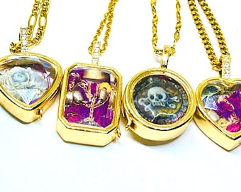 May include: Four gold-toned necklaces with unique pendants. The pendants include a heart with a white rose, a rectangular pendant with purple accents, a round pendant with a skull and crossbones, and a heart with purple accents. Each pendant is on a gold chain.