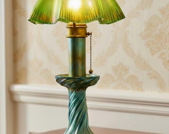 May include: A vintage table lamp with a green glass shade and a teal-colored base. The shade has a ruffled edge and the base features a twisted design. The lamp has a brass-colored neck and a pull chain. The lamp is on a wooden table.