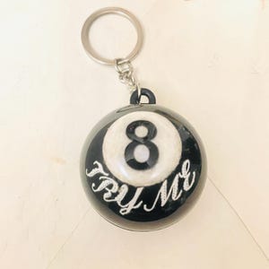 May include: Black and white 8-ball keychain with the words "Try Me" written on it.