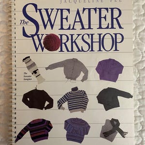 May include: A spiral-bound book titled "The Sweater Workshop" by Jacqueline Fee. The cover features the title in large blue letters with a red yarn ball. Illustrations of various sweaters in different colors and styles are displayed.