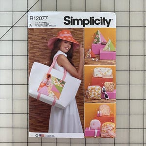 May include: Simplicity sewing pattern R12077 featuring a woman wearing a wide-brimmed orange hat and carrying a white tote bag with a patchwork design. The pattern includes instructions for making various bags and accessories.
