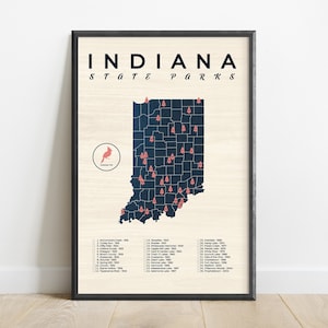 May include: A black and white map of Indiana with red pine tree icons marking the locations of state parks. The map is framed in a black frame and has the text "INDIANA STATE PARKS" at the top. A red cardinal bird icon is in the lower left corner.