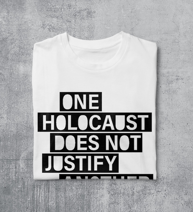 May include: White t-shirt with black text that reads "ONE HOLOCAUST DOES NOT JUSTIFY ANOTHER"