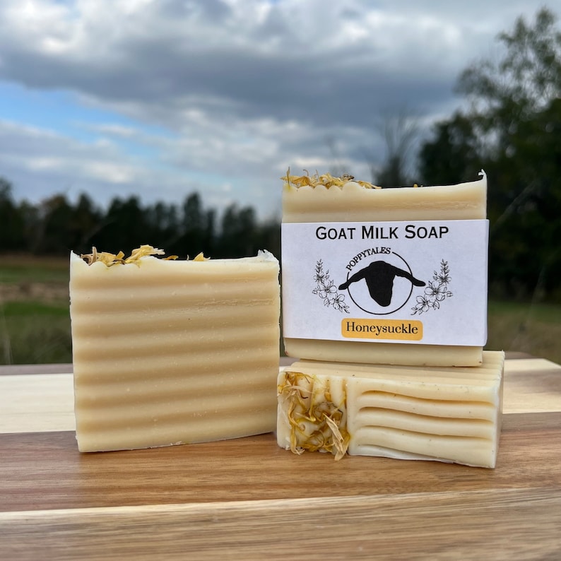 May include: Three bars of goat milk soap with a label that reads "Goat Milk Soap" with a goat silhouette and the words "Poppytales" and "Honeysuckle".