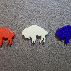 May include: Three buffalo silhouette magnets in red, white, and blue.