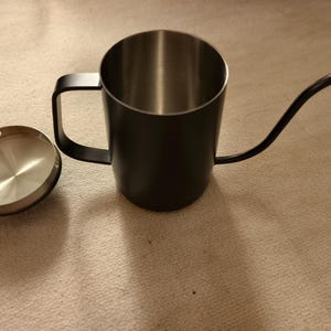 Puede incluir: Una tetera de cuello de cisne negra con interior de acero inoxidable y tapa a juego. La tetera tiene un pico largo y curvo y un asa para verter f&aacute;cilmente. Ideal para preparar caf&eacute; o t&eacute;.