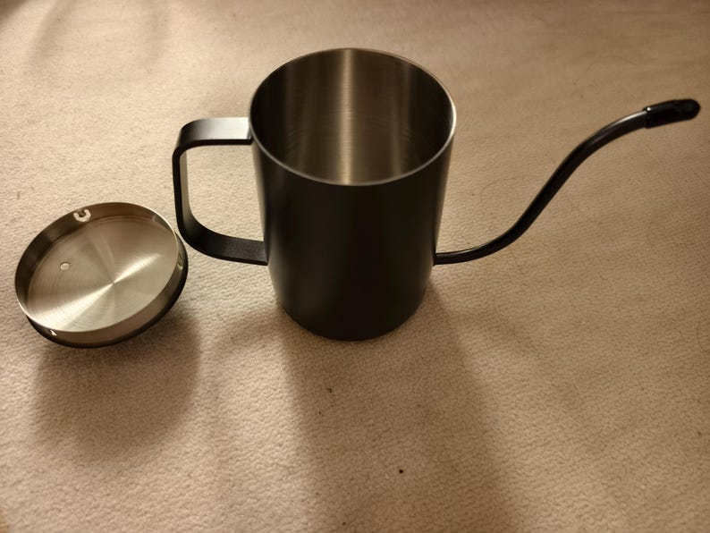 Puede incluir: Una tetera de cuello de cisne negra con interior de acero inoxidable y tapa a juego. La tetera tiene un pico largo y curvo y un asa para verter f&aacute;cilmente. Ideal para preparar caf&eacute; o t&eacute;.