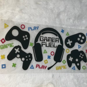 May include: A clear sticker featuring black controller graphics, a headset, and the words "GAMER FUEL." Colorful shapes and the words "PLAY" and "GAME" are also included. This sticker is perfect for gamers.